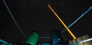 The experiment on La Palma: The laser beam (yellow) generates an artificial guide star in the mesosphere. This light is collected in the receiver telescope (front left). The laser source and the receiver telescope are eight meters away from each other. Credit: Copyright Felipe Pedreros Bustos