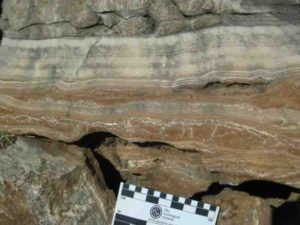 Field photograph of massive flowstone layers from one of the South African hominin caves, with red cave sediments underneath.