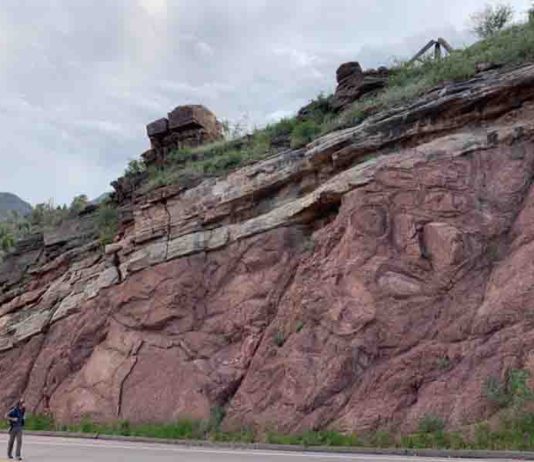 Francis Macdonald walks along a road near Manitou Springs, Colorado, where an exposed outcrop shows a feature known as the "Great Unconformity."