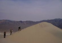 Physics of booming and burping sand dunes revealed