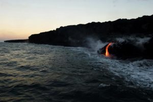 In this Tuesday, Aug. 9, 2016 photo, lava from Kilauea, an active volcano on Hawaii's Big Island, flows into the ocean as seen from a boat operated by Lava Ocean Tours off the coast of Volcanoes National Park near Kalapana, Hawaii. The current lava flow erupted from a vent on the volcano in May and made its way to the sea in late July. Visitors can hike about 10 miles round trip to see the lava flow, or take a boat or helicopter tour to see the flow. (AP Photo/Caleb Jones)