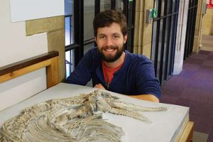 Jonathan Hanson with the ichthyosaur skeleton at the School of Earth Sciences. Credit: University of Bristol 