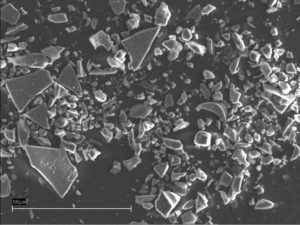 An electron scanning microscope picture of an ash sample from a 55,500 years old ash layer in the NGRIP ice core. The ash shards are the larger pieces that look like broken glass. The colours are not true. The white bar at the bottom left represents 1/10 mm. Credit: University of Copenhagen