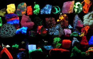 Collection of various fluorescent minerals under ultraviolet UV-A, UV-B and UV-C light. Chemicals in the rocks absorb the ultraviolet light and emit visible light of various colors, a process called fluorescence. Credit: Hannes Grobe/AWI