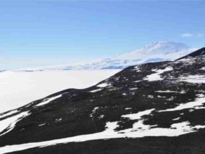 Rock samples collected near the Antarctic volcano Mount Erebus, seen here in the distance, harbor fingerprints of Earth’s ancient magnetic field. A new analysis delves into discrepancies between these fingerprints and predictions from a long-standing approximation of the field. Credit: Hanna Asefaw