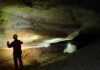 Unearthing the sources of cave-forming sulfuric acid Dimitri Laurent explores a typical gallery in the Nébélé Cave, which was formed by sulfuric acid speleogenesis. You can see a deep notch that indicates the former presence of a river, and sodium sulfate on the left that is produced from weathering by sulfuric acid. Credit: Christophe Durlet