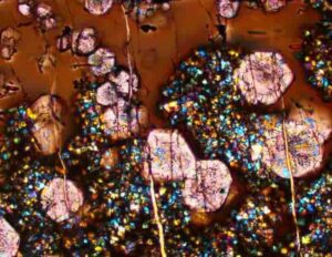 A microscope image from an experiment conducted for this study. The image contains glass (brown), large garnets (pink) and other small mineral crystals. The field of view is 410 microns wide, about size of a sugar crystal. Credit: Science (2023). DOI: 10.1126/science.ade3418
